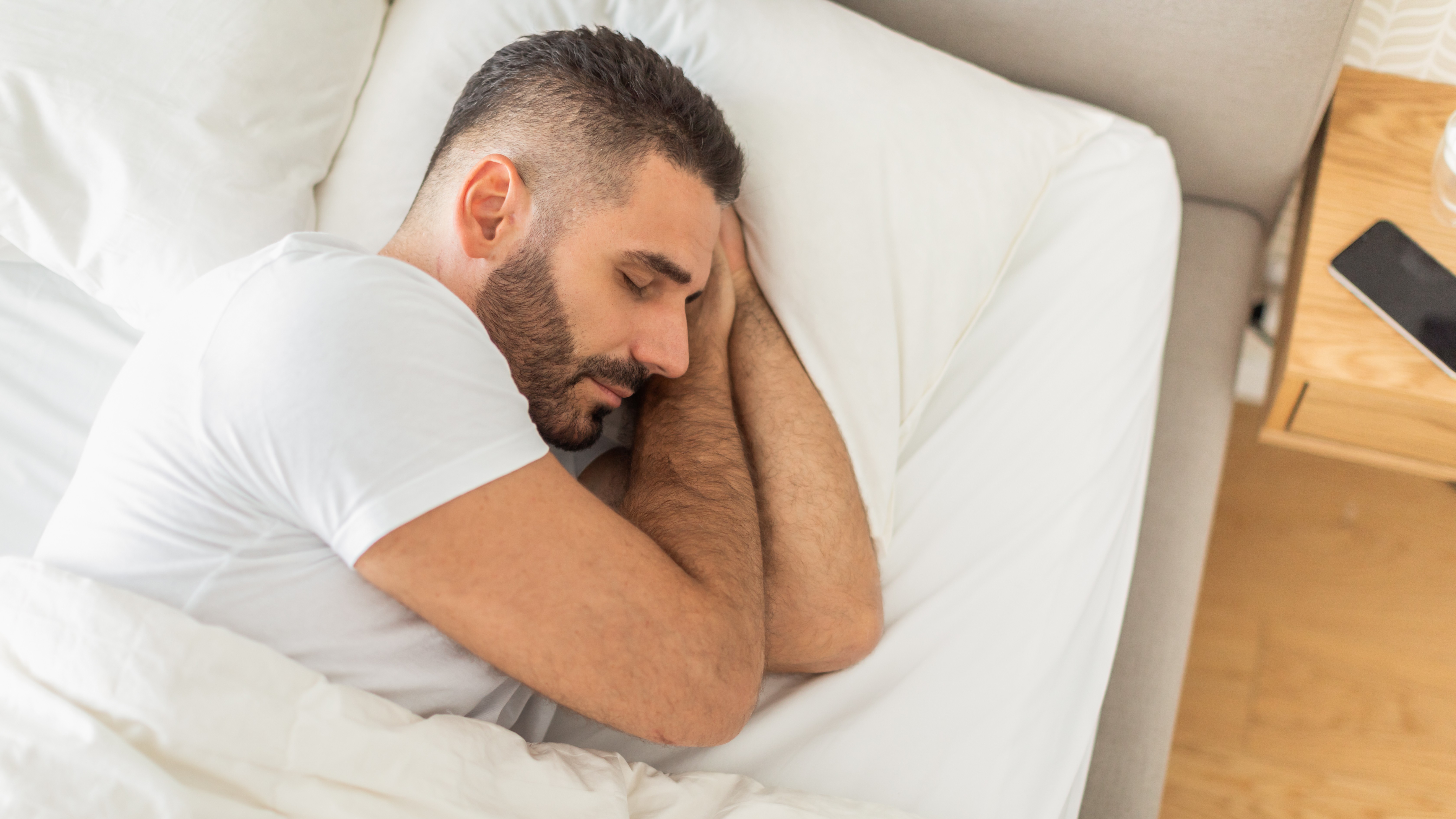 Man Sleeping in Bed With White Sheets and Pillows